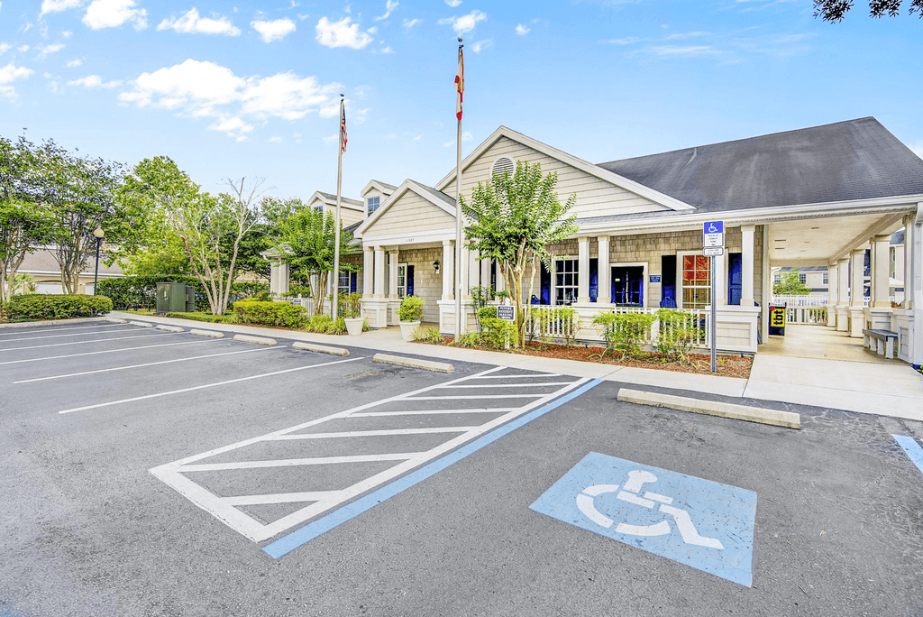 Clubhouse front entrance featuring blue trim, flag poles, and native surrounding landscape.